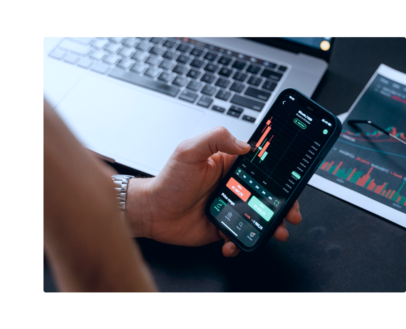 hand holding smartphone displaying financial trading app with graphs